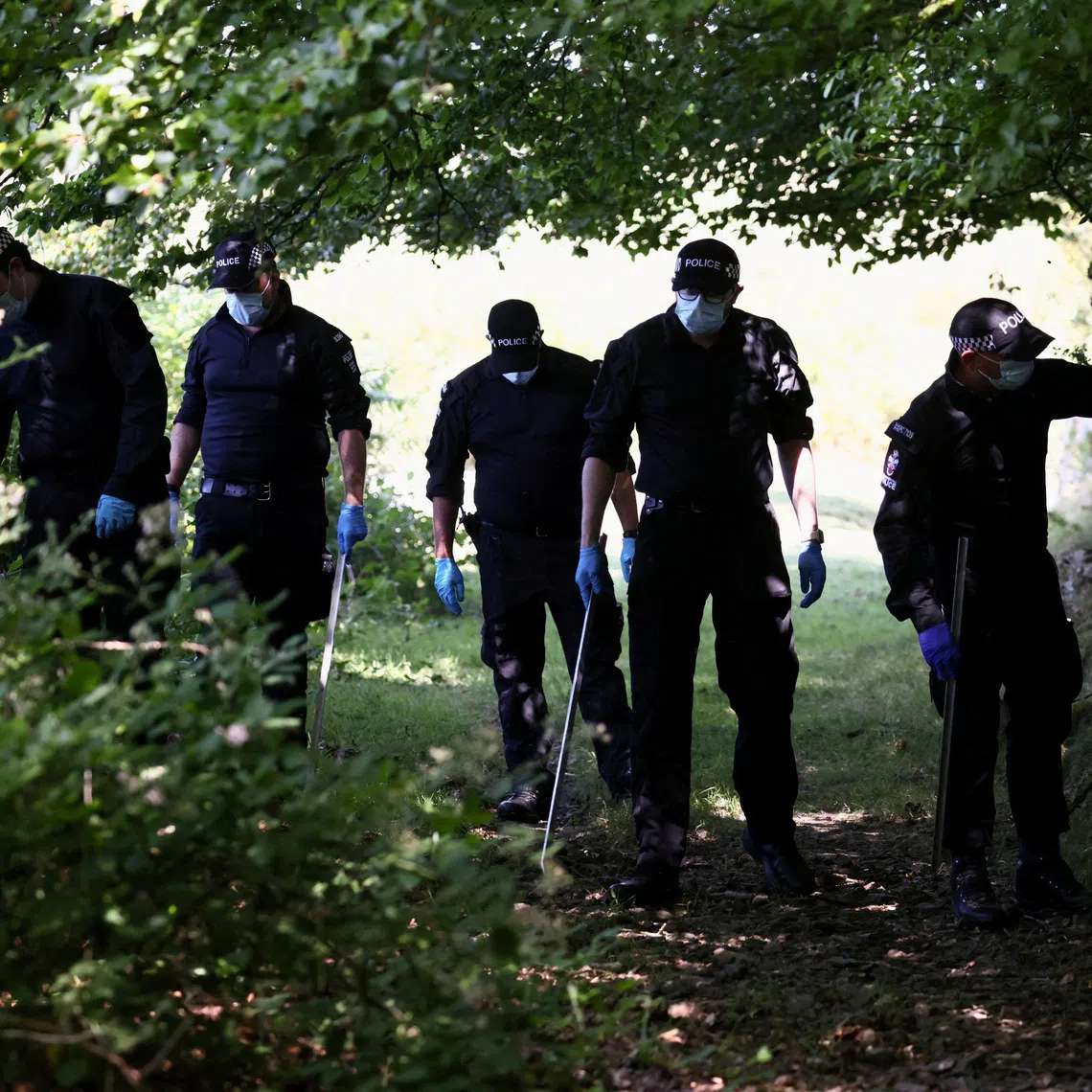 Police officers investigate the area near the home of Ann Widdecombe after she was found dead on July 11.