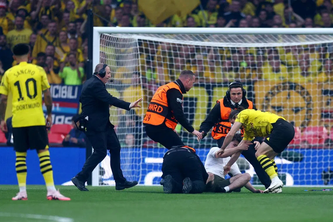 A pitch invader is detained by stewards and Borussia Dortmund's Marcel Sabitzer during the Champions League final against Real Madrid at Wembley Stadium in London on  June 1, 2024.