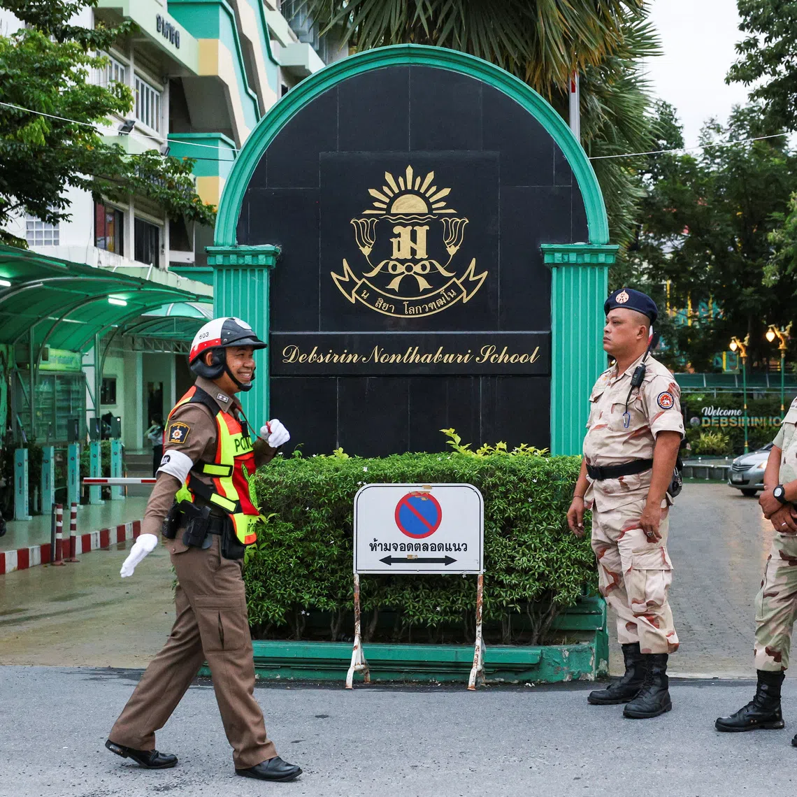 A police officer and civil defence volunteers stand guard at the entrance of Debsirin Nonthaburi School on Sept 1.