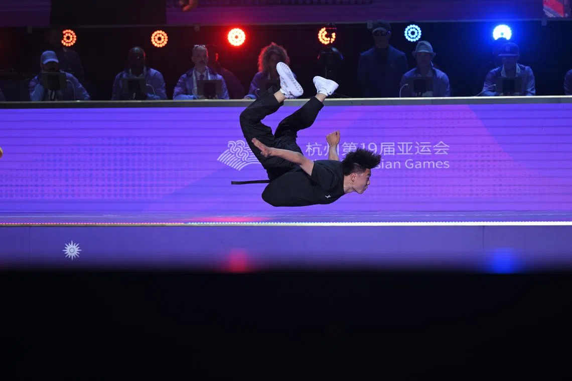 A breakdancer flies as the judges watch during the sports' debut at the Asian Games.