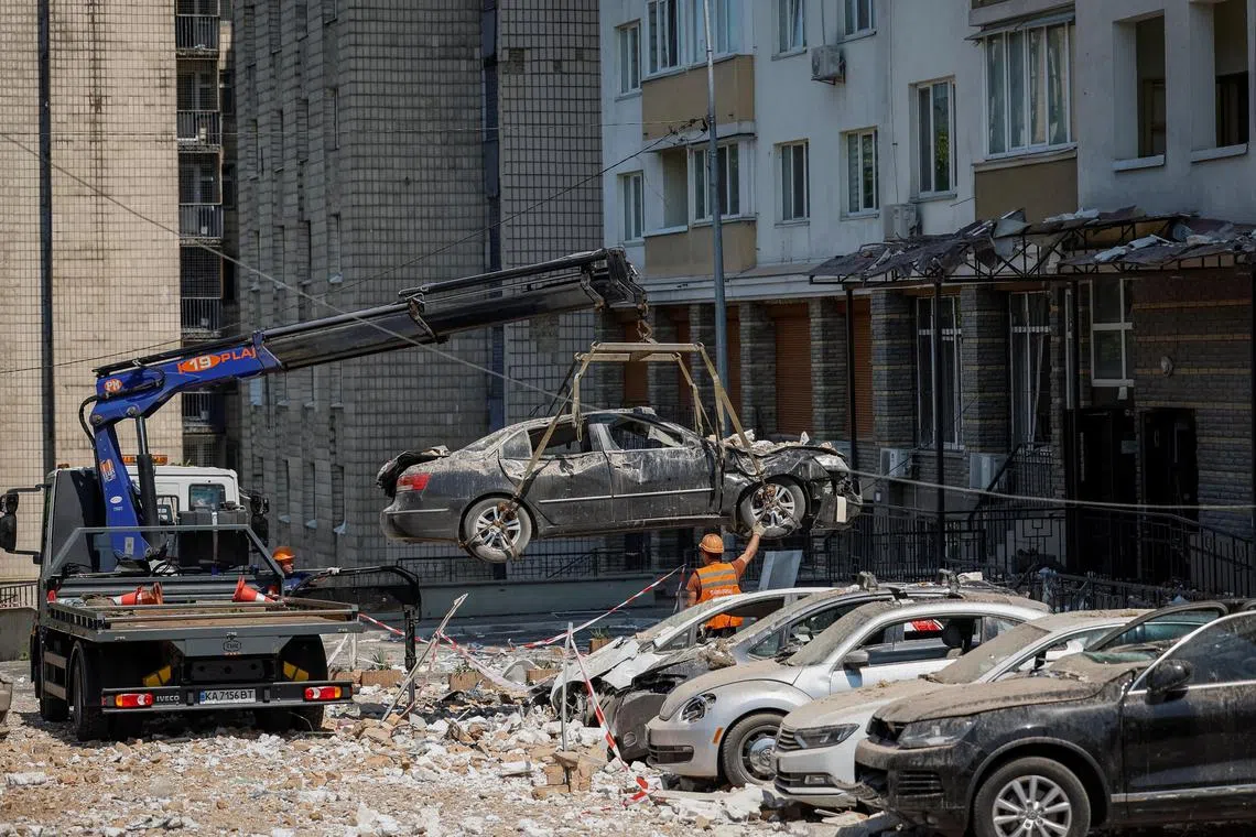 Destroyed cars are removed in Kyiv, following a large Russian drone strike in May 2023.