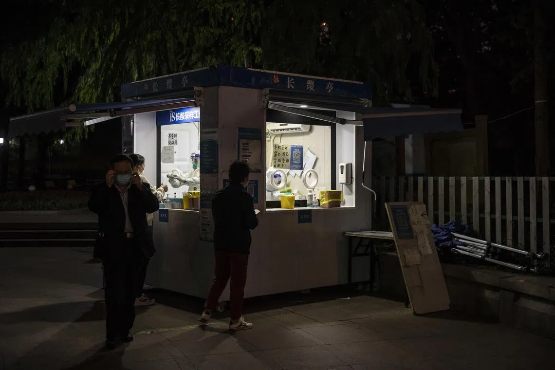 People at a Covid-19 testing facility at night in Shanghai. A gradual relaxation of Covid control measures may have a more positive impact on the economy, says the writer. 