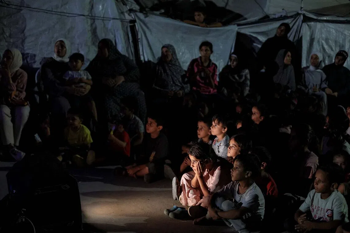 Palestinian children watch a cartoon film projected on a screen during a mobile cinema screening organized by the Masharawi Foundation for Cinema and Filmmakers at a tent camp sheltering displaced people in Gaza City, September 2, 2026. REUTERS/Dawoud Abu Alkas TPX IMAGES OF THE DAY