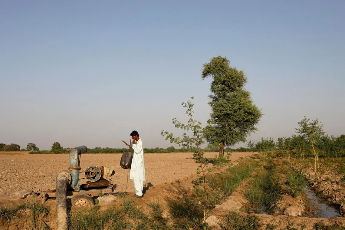 A farmer stands beside a draining pump following rains and floods during monsoon season in Kunri, Pakistan, on Oct 15, 2022.