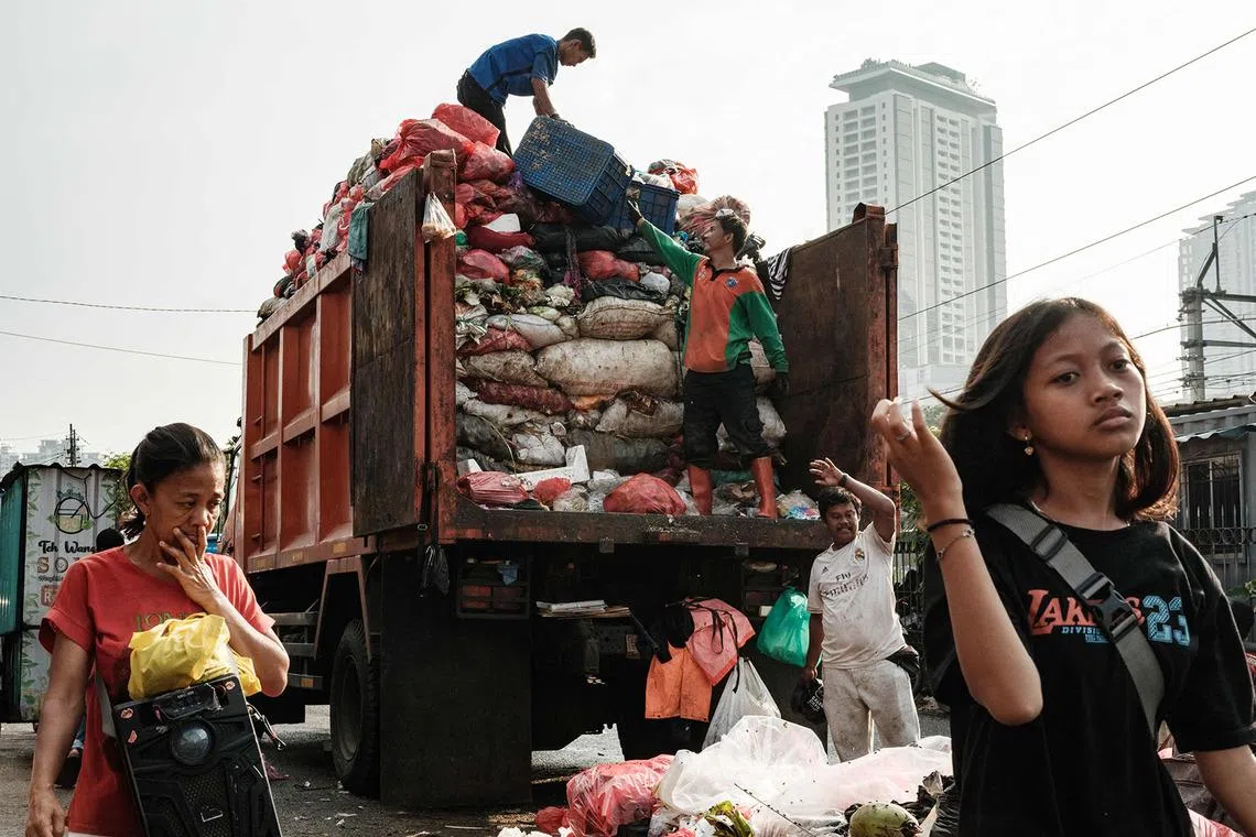 TOPSHOT - Workers load trash from a street in Jakarta on April 4, 2026. (Photo by YASUYOSHI CHIBA / AFP)