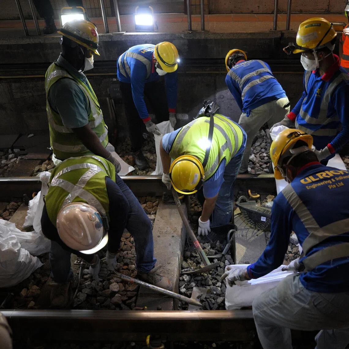 Workers digging up the old ballast in between sleepers during the ballast renewal process at Bishan MRT Station in the early hours of Dec 11.