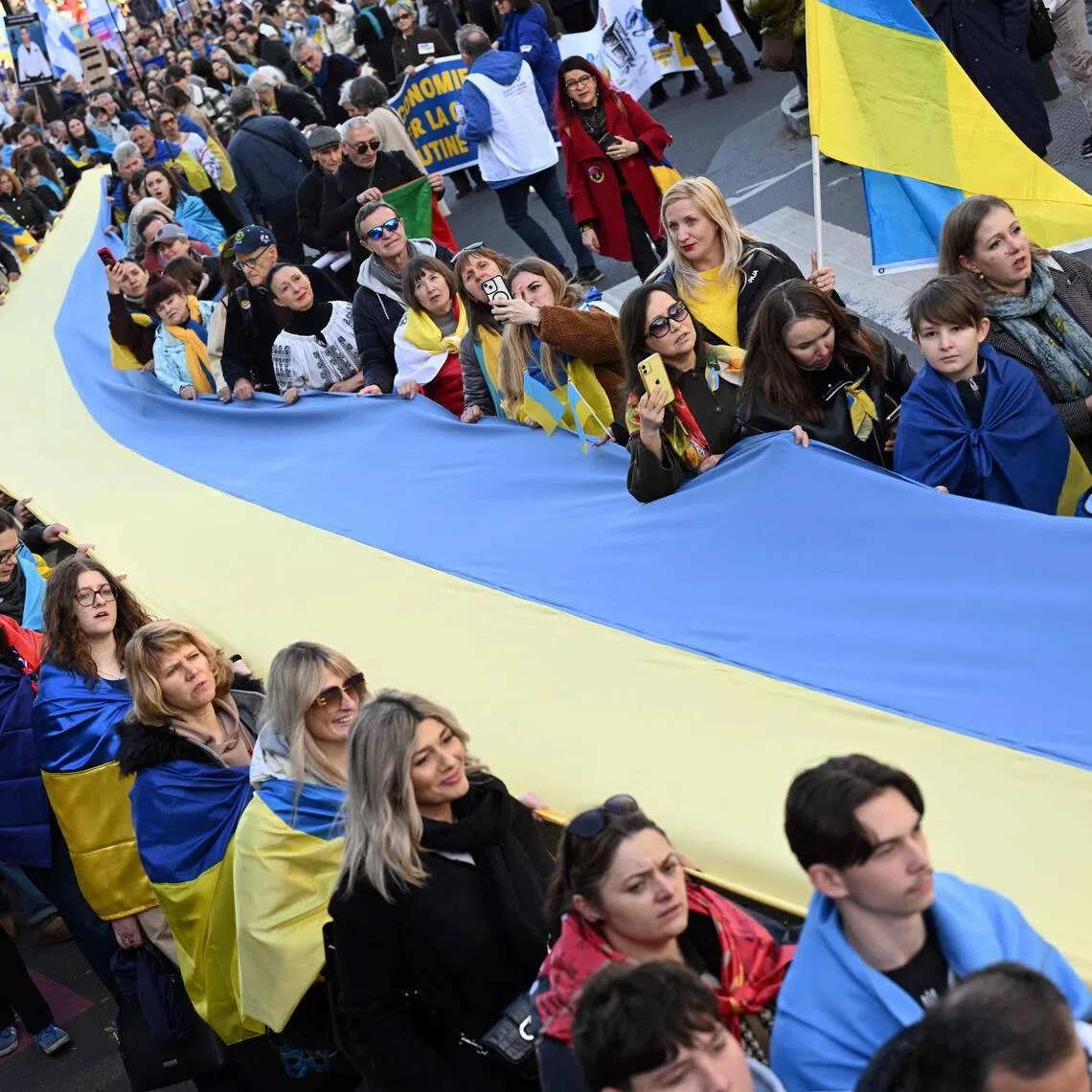 People hold a giant Ukrainian flag during a march for Ukraine ahead of the fourth anniversary of Russia's invasion, in Paris on Feb 21.