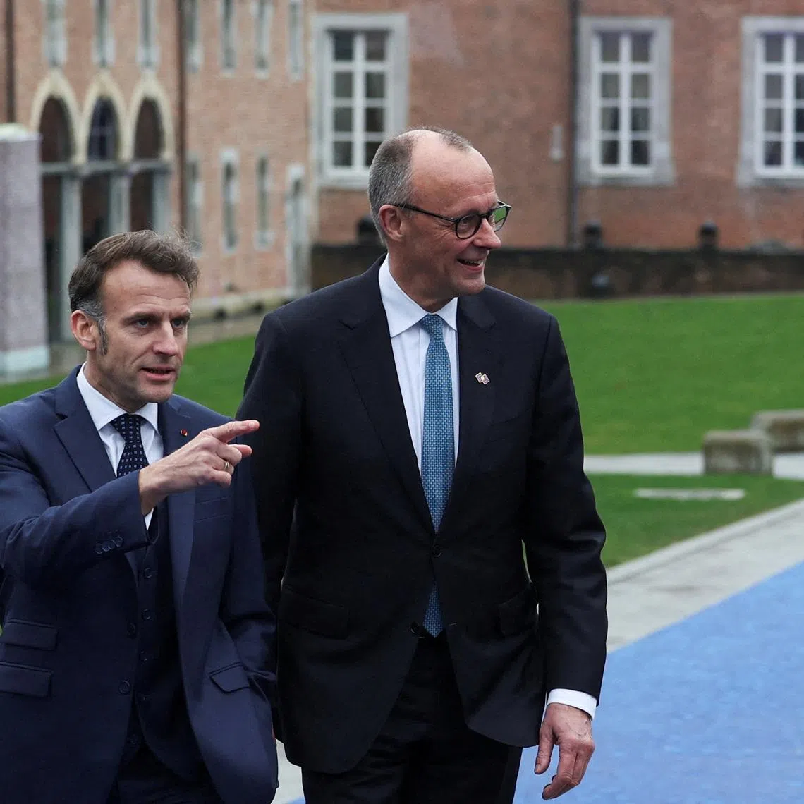 Germany's Chancellor Friedrich Merz and France’s President Emmanuel Macron walk at Alden Biesen castle, on the day of an informal European Union leaders retreat, Belgium, February 12, 2026. REUTERS/Murad Sezer