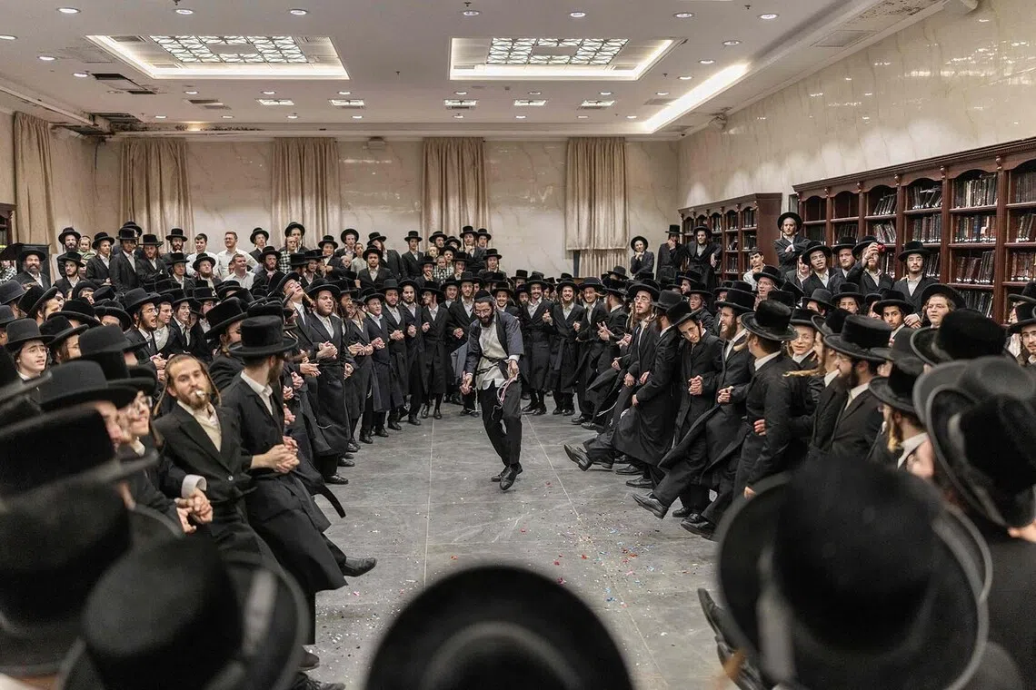 TOPSHOT - Ultra-Orthodox Jewish men dance as they celebrate the release from military prison of a fellow yeshiva student, who was detained for not appearing after being called up for Israeli military service, in Elad on August 31, 2026. Israel's Supreme Court suspended in July a contentious law passed earlier that month that would have blocked the arrest of Jewish ultra-Orthodox men who refuse military service. Leaders of the insular ultra-Orthodox community have long opposed the conscription of its members, arguing that army service would pull young men away from religious study and erode their way of life. But calls to draft them have intensified in recent years as Israel has become embroiled in multiple wars. (Photo by ilia YEFIMOVICH / AFP)