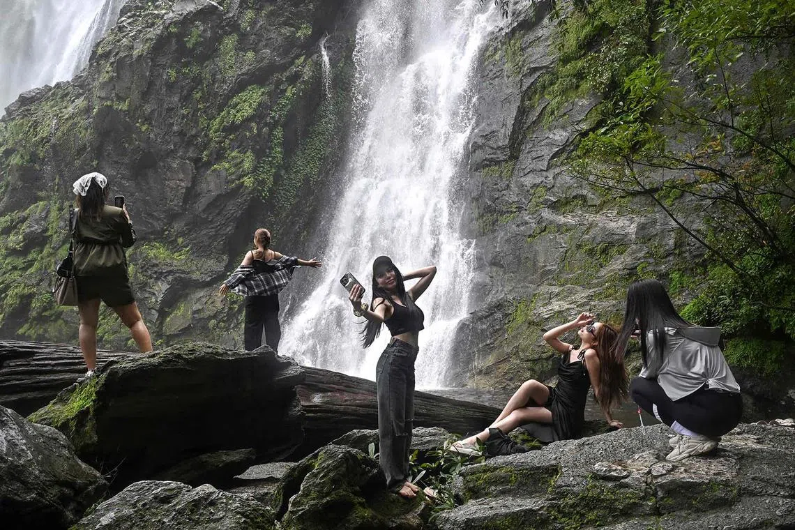 Visitors taking pictures at Khlong Lan waterfall in Khlong Lan National Park in Thailand's upper central Khampaeng Phet province on June 10, 2025. 