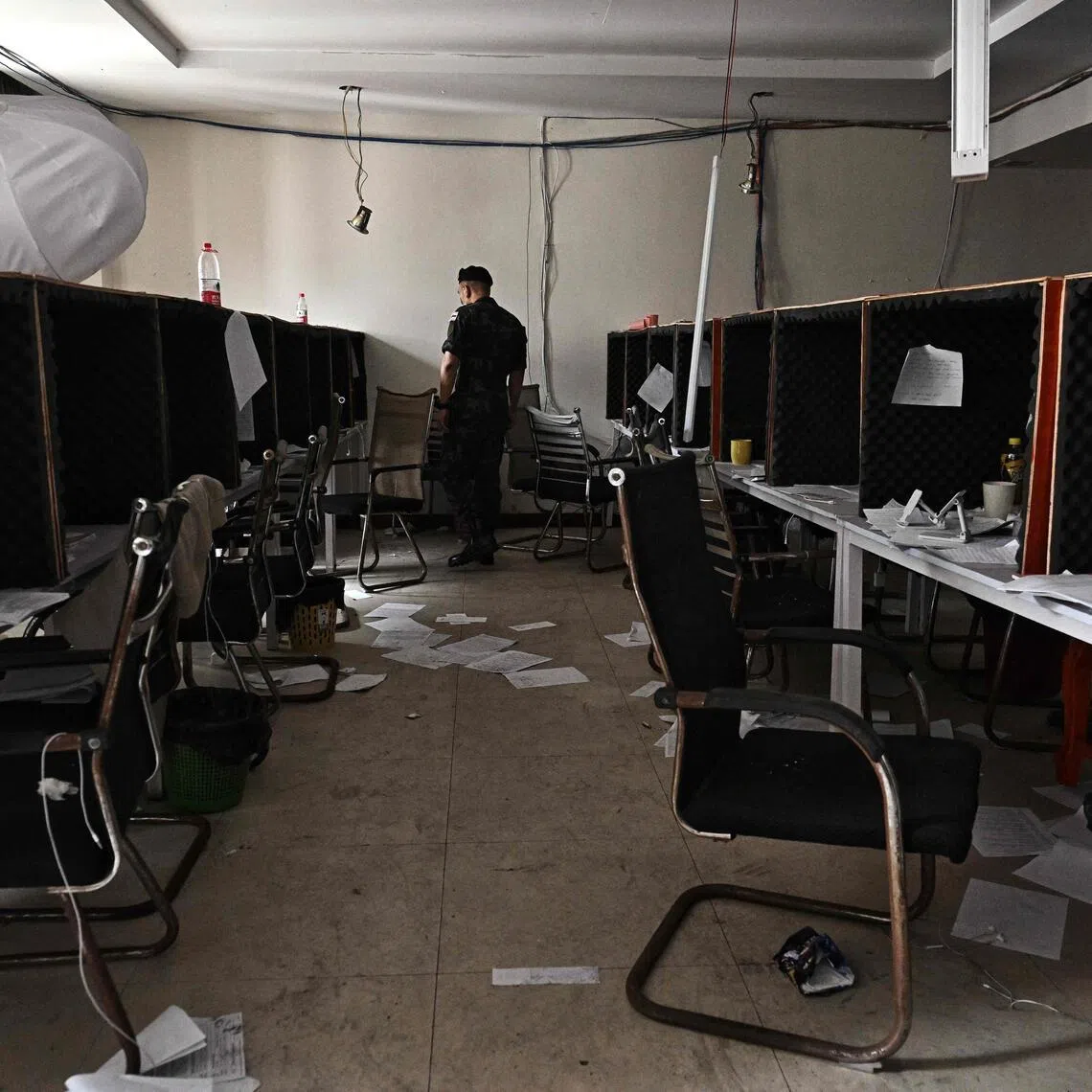A Royal Thai Army officer looks at work booths inside an abandoned scam centre in O'Smach town on the Thai-Cambodian border.