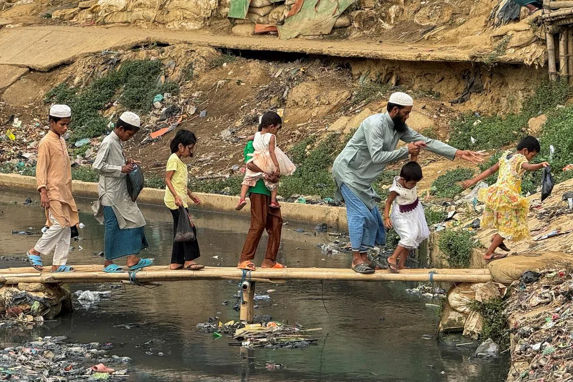 FILE PHOTO: Rohingya refugees cross a bamboo-made bridge during an ongoing heatwave in Cox's Bazar, Bangladesh, May 2, 2024. REUTERS/Ro Yassin Abdumonab/File Photo
