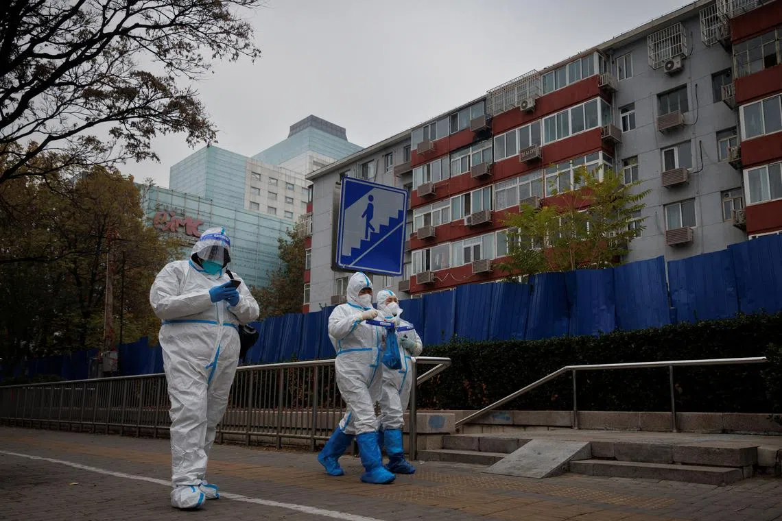 Pandemic prevention workers in protective suits walk outside a locked-down residential compound in Beijing on Nov 18. 
