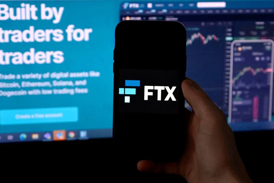 (FILES) In this file photo taken on February 09, 2022 (FILES) In this file photo illustration taken on February 09, 2022, shows a smart phone screen displaying the logo of FTX, the crypto exchange platform, with a screen showing the FTX website in Arlington, Virginia. - A day after it filed for bankruptcy, the deeply troubled cryptocurrency platform FTX said on November 12, 2022, it had taken action to halt what it said were "unauthorized transactions." The company took "precautionary steps to move all digital assets to cold storage... to mitigate damage upon observing unauthorized transactions," FTX's general counsel, Ryne Miller, said on Twitter. (Photo by OLIVIER DOULIERY / AFP)