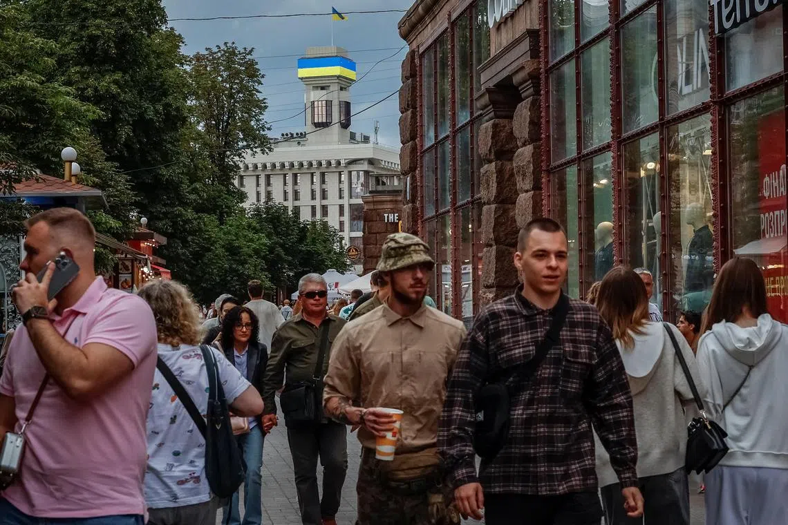 People walking in the main street of the Ukrainian capital, on Aug 23, with a digital screen in the background displaying the colours of the Ukrainian flag.