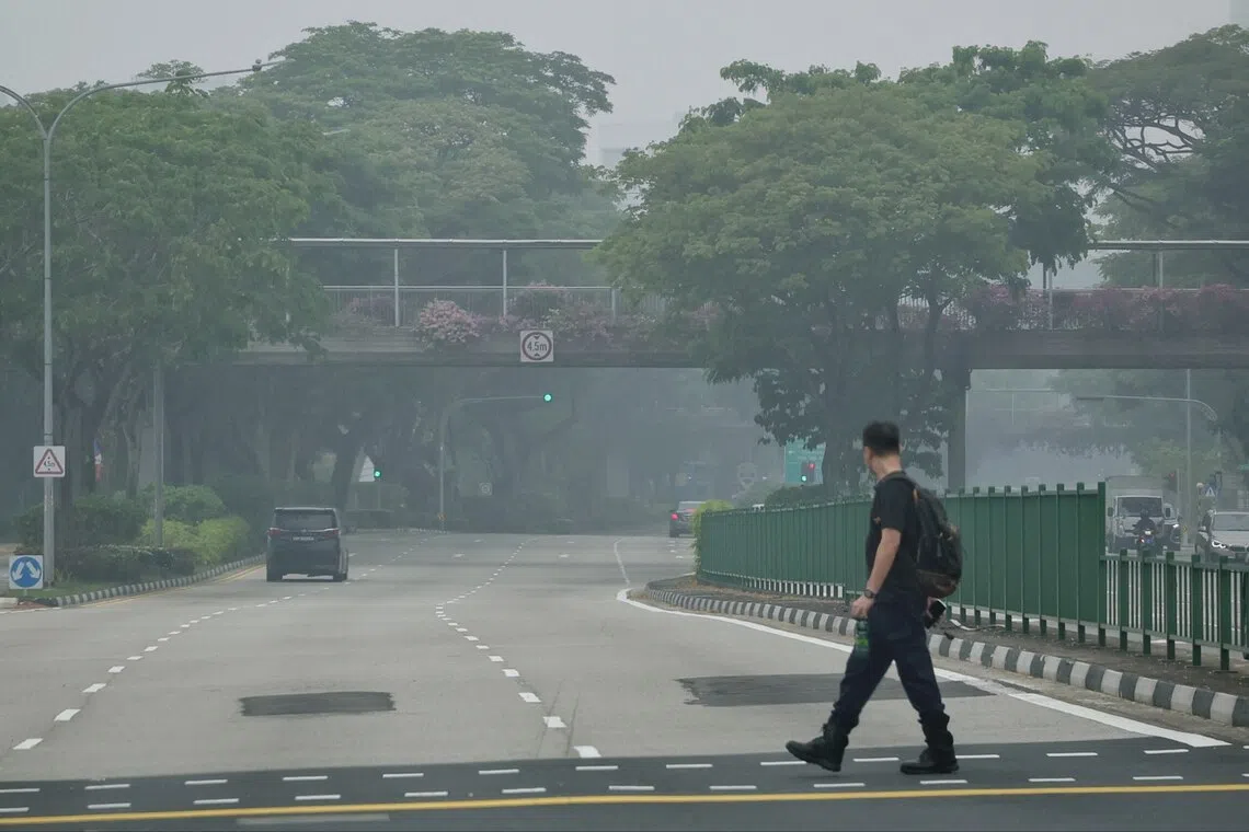 A pedestrian crossing a traffic junction along Clementi Road in hazy conditions at 1.05pm on Oct 14.