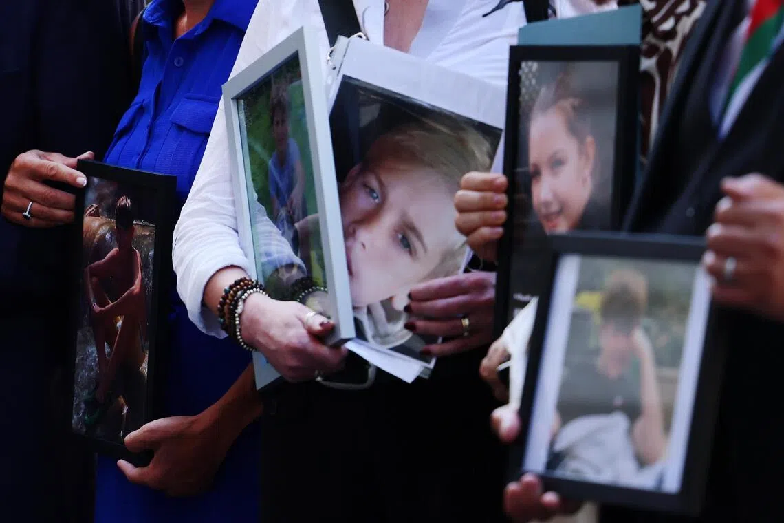 Bereaved parents in London hold portraits of their children who they say died as a result of social media business practices.
