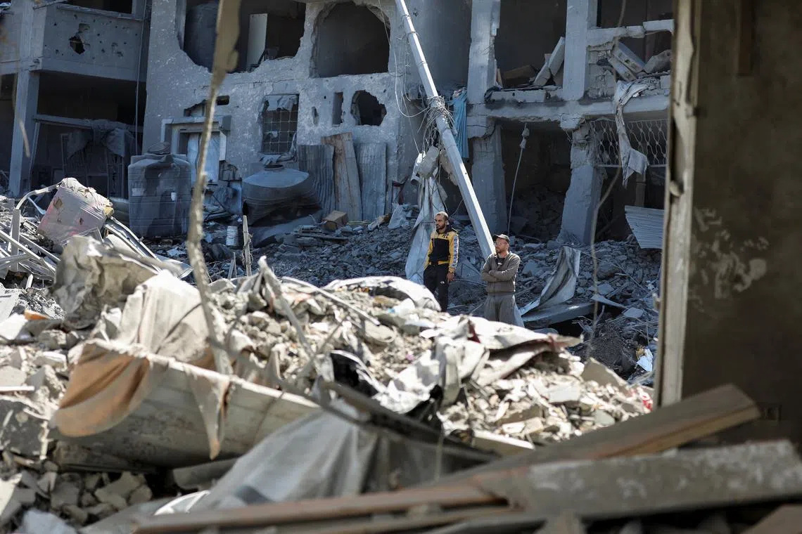 Palestinians stand at the site of an Israeli strike on a house, in Gaza City, March 24, 2025. REUTERS/Dawoud Abu Alkas