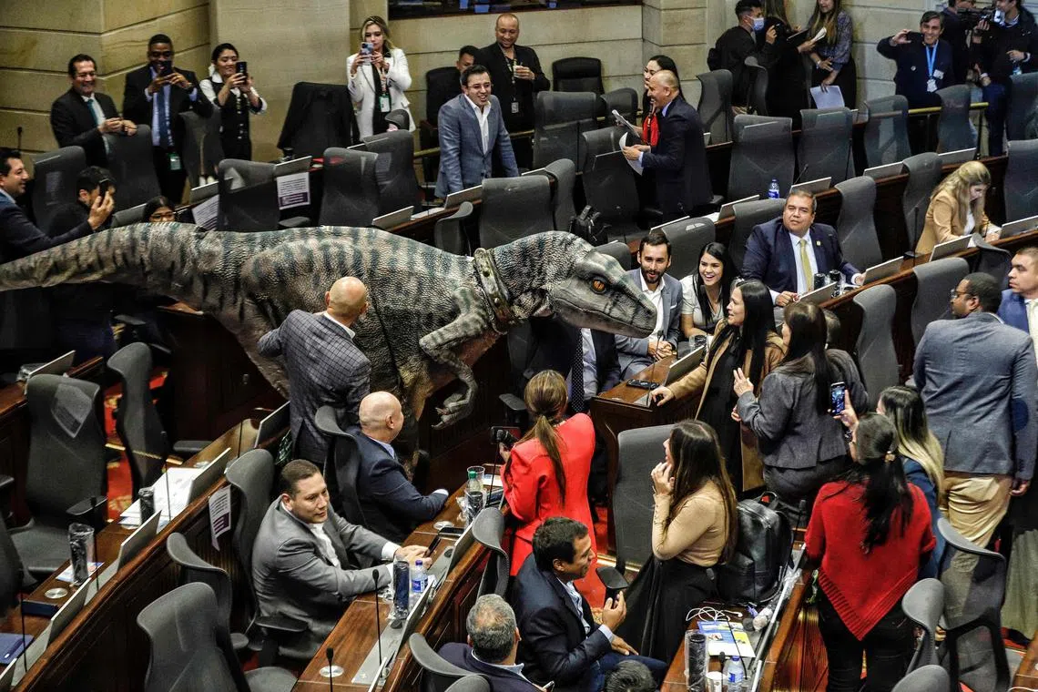 A person in a dinosaur costume making an appearance at the Colombia Congress during a debate on climate change, in Bogota on June 13, 2023. The demonstrator in dinosaur costume also held a sign reading "Don't Choose Extintion." 