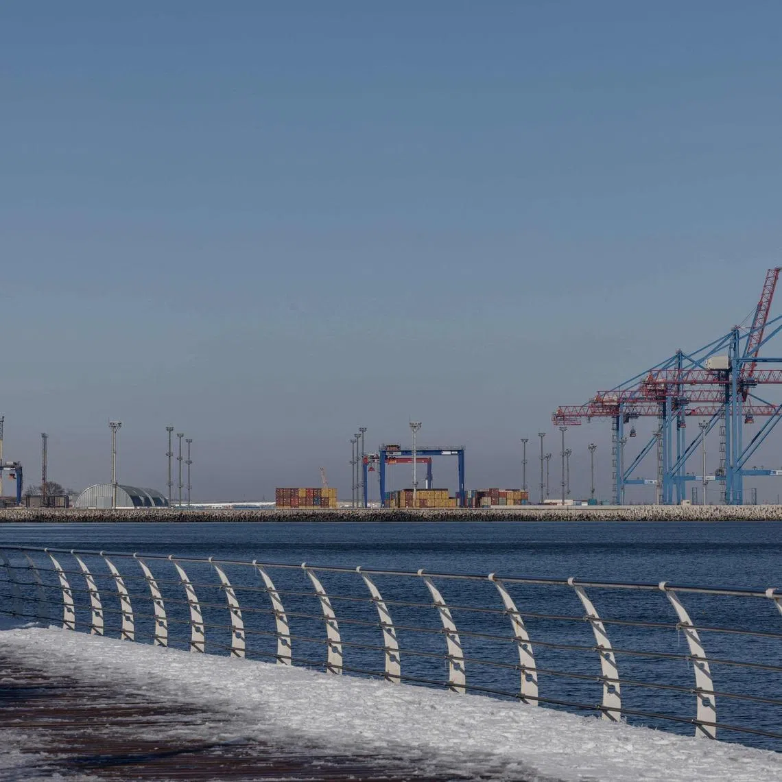 A pedestrian walks on the embankment of the sea port of Odesa on February 19, 2026. The main gateway to the Black Sea and beyond, Odesa is a key logistics hub for Ukraine, one of the world's top agricultural exporters. Russia has intensified its attacks on the region - tripling the number of missile and drone strikes over the last year in what officials call an attempt to cut Ukraine off from the sea. (Photo by Oleksandr GIMANOV / AFP)
