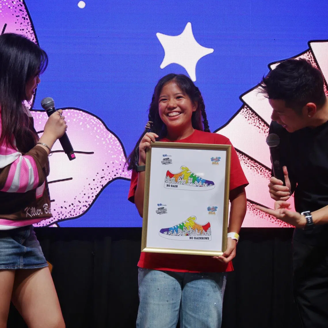 ST20250223_202503900136/akdesign24/Adrielle Koh/Jason Quah

Winner of the Design Your Sneaker competition Sarah Gwee, 19, receives a framed illustration of her design from
emcees Kiss 92 FM DJs Shawnia Seah and Tim Oh at Sneaker Con SEA on Feb 23, 2025. ST PHOTO: JASON QUAH