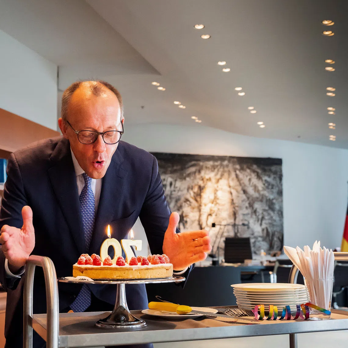 German Chancellor Friedrich Merz blows out some candles on a birthday cake he received by staff of the Chancellery on the occasion of his 70th birthday in Berlin, Germany, November 11, 2025.   Steffen Kugler/BPA/Handout via REUTERS