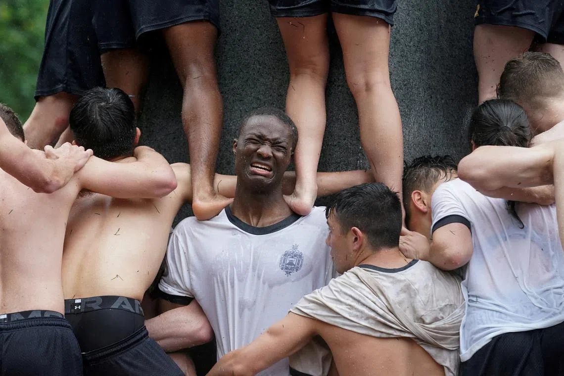 A member of U.S. Naval Academy's first year class holding up fellow cadets to climb the Herndon Monument, a granite obelisk coated with a thick layer of oil in Annapolis, Maryland, U.S., on May 15, 2024.