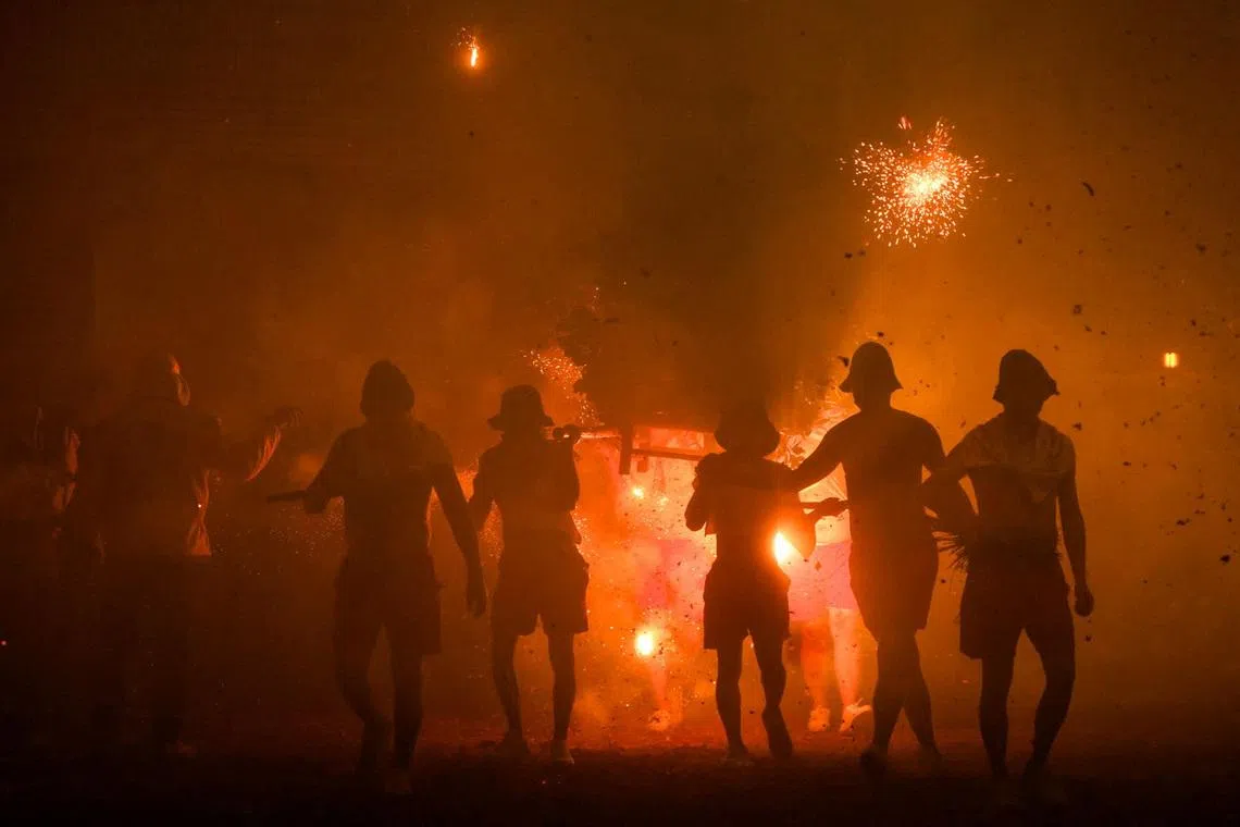 Volunteers letting themselves be pelted with thousands of exploding firecrackers while carrying Lord Handan across the street as part of the Lantern Festival celebrations in Miaoli, Taiwan, on March 3, 2026.