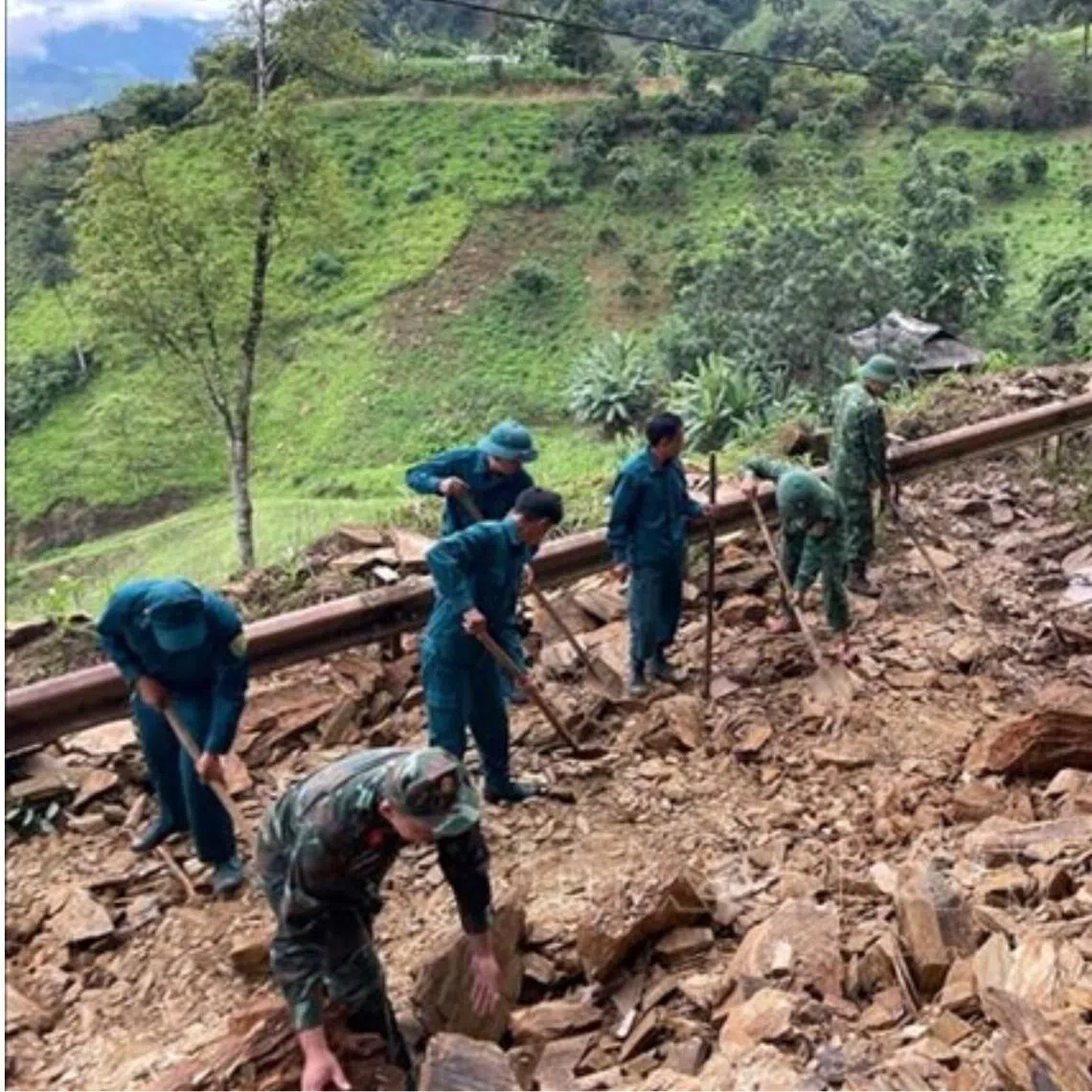 Soldiers clearing rocks and debris to ensure safe traffic flow after a landslide in Vietnam.