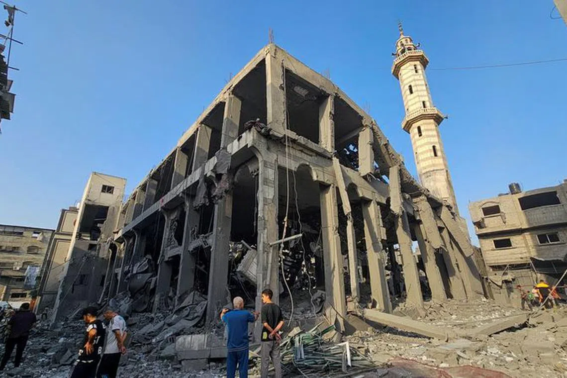 Palestinians gather around the remains of a mosque destroyed in Israeli strikes, as the conflict between Israel and Palestinian Islamist group Hamas continues, in the northern Gaza Strip October 22, 2023. REUTERS/Anas al-Shareef