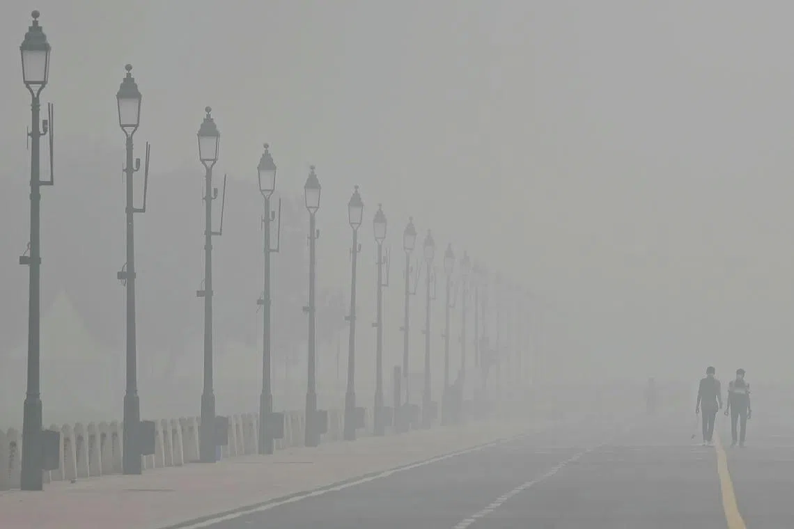 People walking along the Kartavya Path amid heavy smoggy conditions in New Delhi on Nov 5, 2023. 