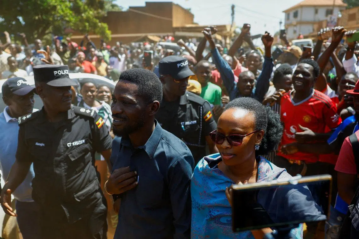 Ugandan Presidential candidate Robert Kyagulanyi, also known as Bobi Wine, of the National Unity Platform (NUP) party, flanked by his wife Barbara Kyagulanyi are escorted by police and supporters as they arrive to cast their votes in the general election, within Magere neighborhood of Kasangati district in Kampala, Uganda January 15, 2026. REUTERS/Thomas Mukoya
