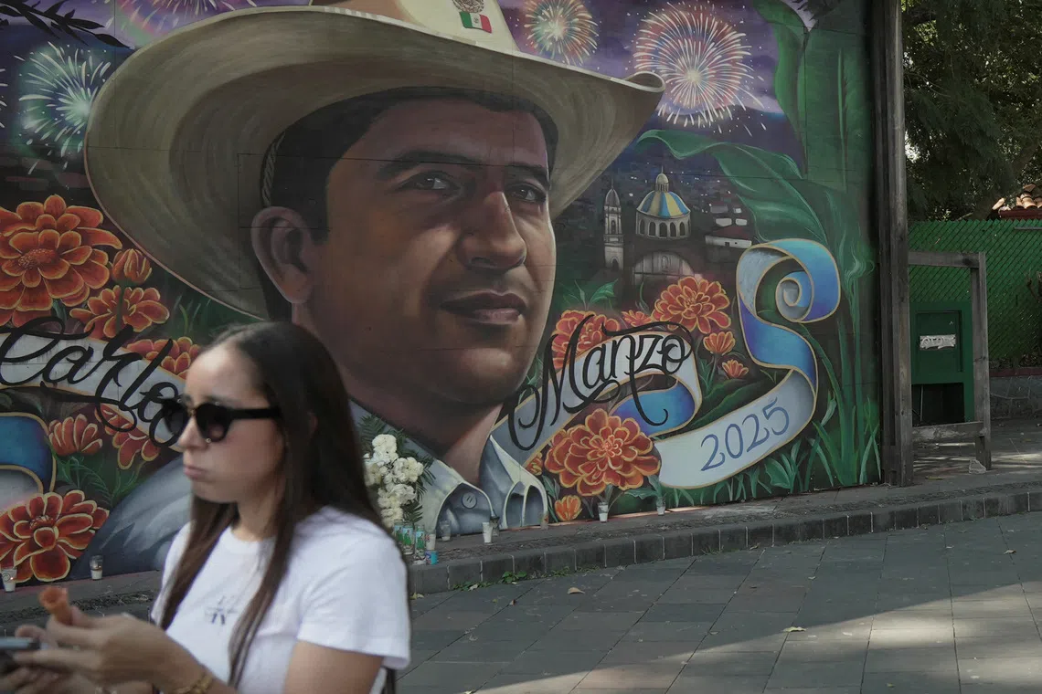 A woman stands near a mural depicting late Mayor Carlos Manzo, who was killed during a Day of the Dead event, in Uruapan, Mexico, November 7, 2025. REUTERS/Ivan Arias