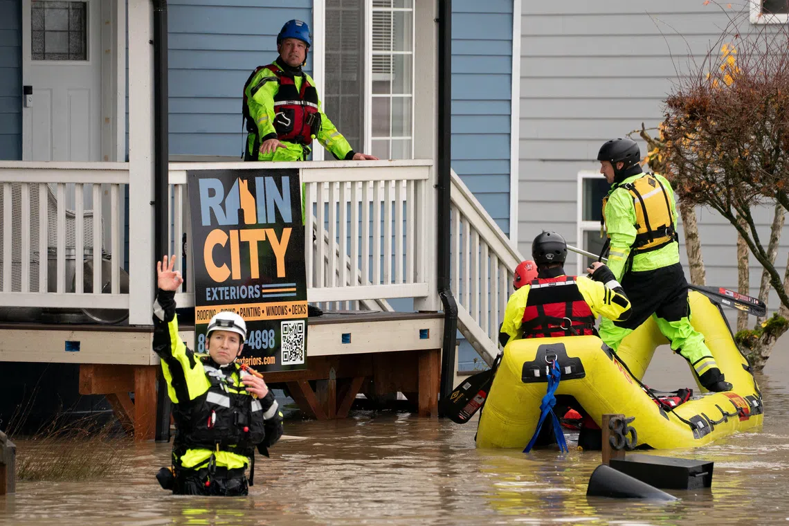 Rescue personnel prepare to evacuate residents from a home in an area flooded by the Snohomish River, in Snohomish, Washington, on Dec 11, 2025.