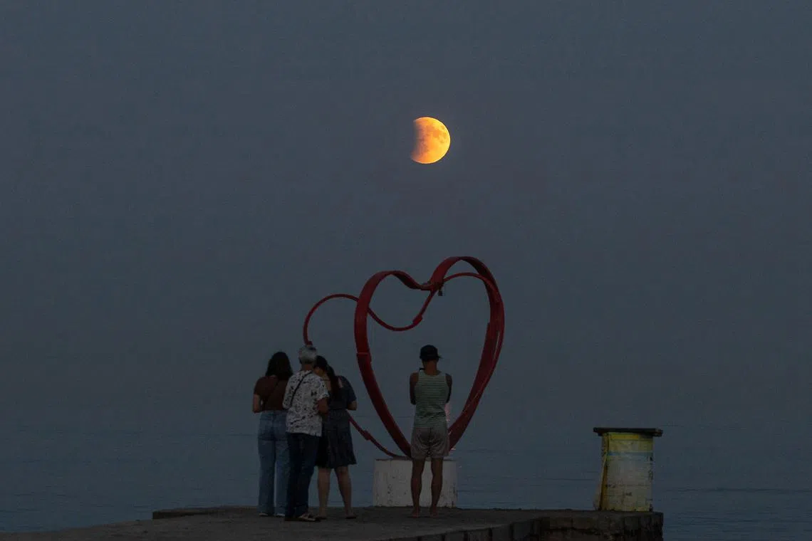 Beach-goers on the shores of the Black Sea observing a full moon, also known as a blood moon, during a total lunar eclipse in Odesa, Ukraine, on Sept 7, 2025.