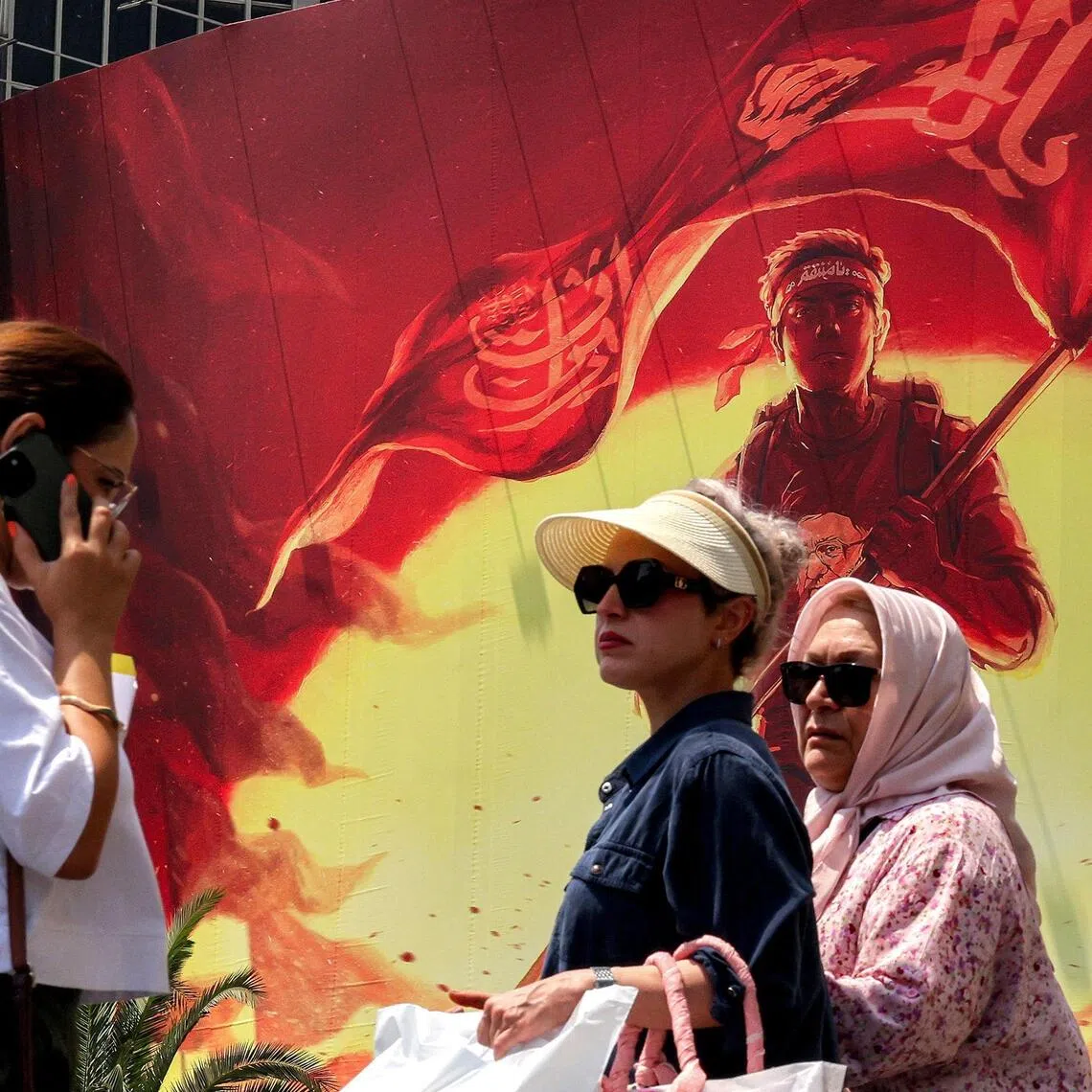 Women walking past a political billboard in central Tehran on Aug 8.