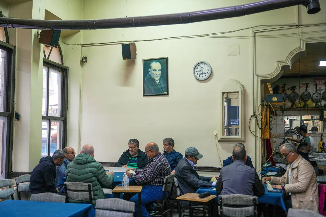 Image 5: People play Turkish rummy, a tile-based game, with a picture of modern Turkey's founder Mustafa Kemal Ataturk on the wall behind them, in the western city of Izmir, an opposition stronghold, Turkey, October 17, 2026. REUTERS/Ali Dinc