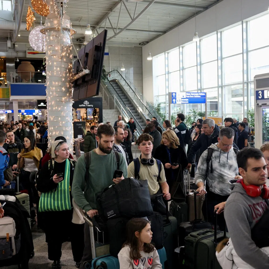 People stand with their luggage, as airports across Greece have suspended arrivals and departures on Sunday, after unspecified issues affecting radio frequencies, at the Eleftherios Venizelos International Airport, in Athens, Greece, January 4, 2026. REUTERS/Louiza Vradi