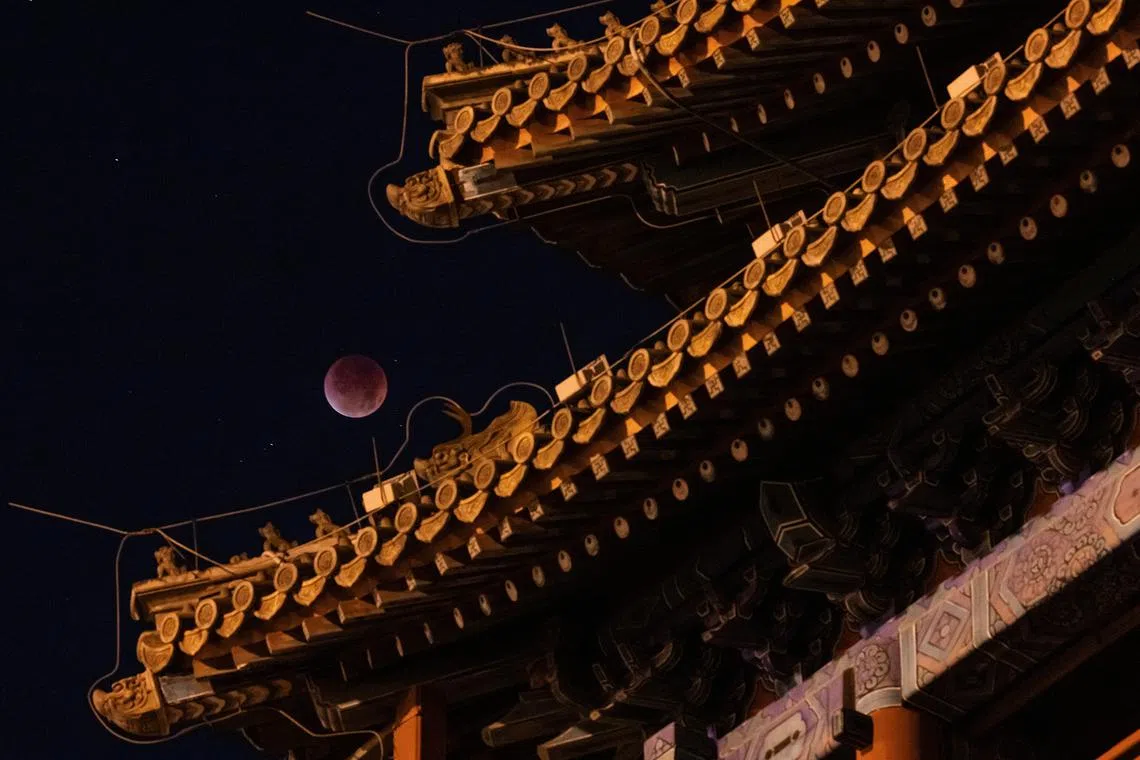 The blood moon is seen over the roof of Yongdingmen Gate on the night of a total lunar eclipse in Beijing, China, on Sept 8, 2025. 
