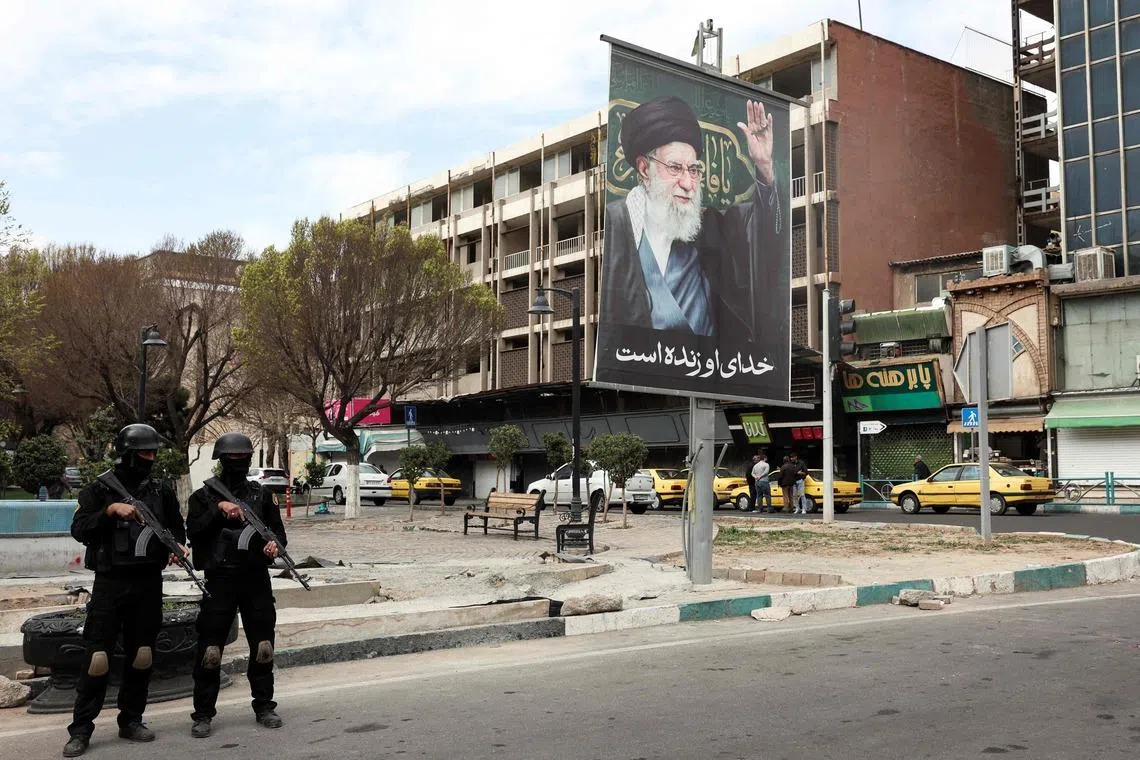 Iranian security forces stand guard on a street next to a billboard of Supreme Leader Ayatollah Ali Khamenei in Tehran on March 2. Mr Khamenei's wife had been in a coms since strikes on Feb 28.