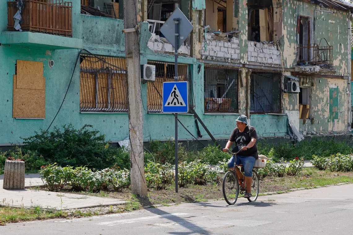 A man rides a bicycle along a street in the town of Kurakhove, in the course of Russia-Ukraine conflict in the Donetsk region, a Russian-controlled area of Ukraine, July 18, 2025.  REUTERS/Alexander Ermochenko