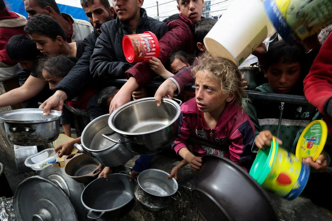 FILE PHOTO: Palestinians with children wait to receive food cooked by a charity kitchen amid shortages of food supplies, as the ongoing conflict between Israel and the Palestinian Islamist group Hamas continues, in Rafah, in the southern Gaza Strip, February 13, 2024. REUTERS/Ibraheem Abu Mustafa/File Photo