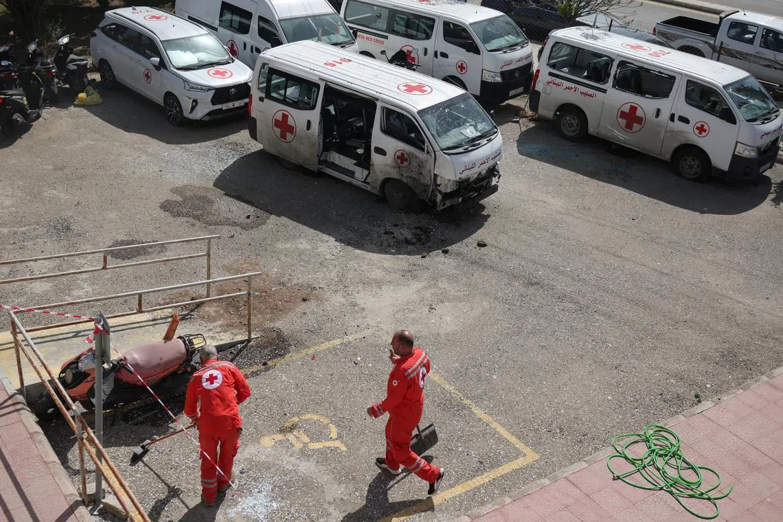 Staff members clean shattered glass after a drone strike damaged vehicles and a building, slightly injuring three workers, in Tyre, Lebanon, April 13, 2026. REUTERS/Louisa Gouliamaki
