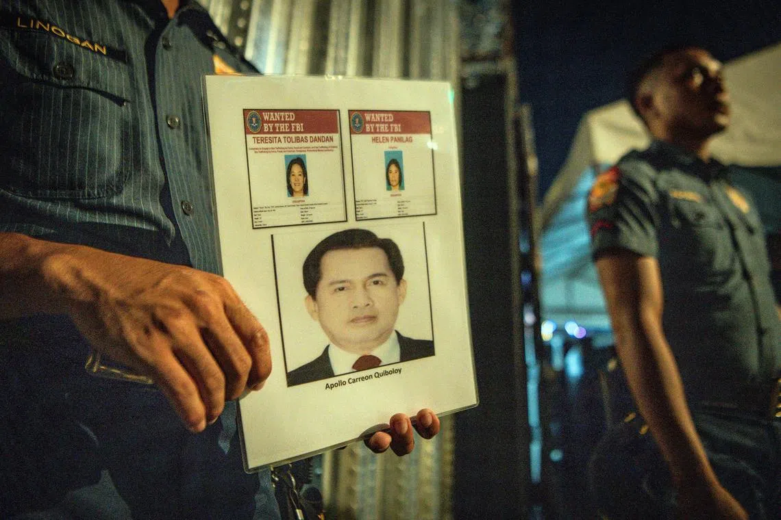 Police holding a poster with pictures of the fugitive Apollo Quiboloy and his associates outside the gates of the Kingdom of Jesus Christ compound in Davao City, Philippines. 