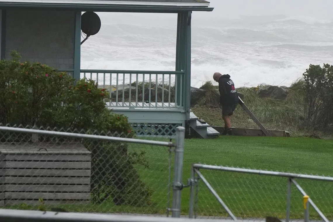 Waves crash ashore as a person works on his house after the arrival of post-tropical storm Lee in Canada's Lockeport, Nova Scotia.