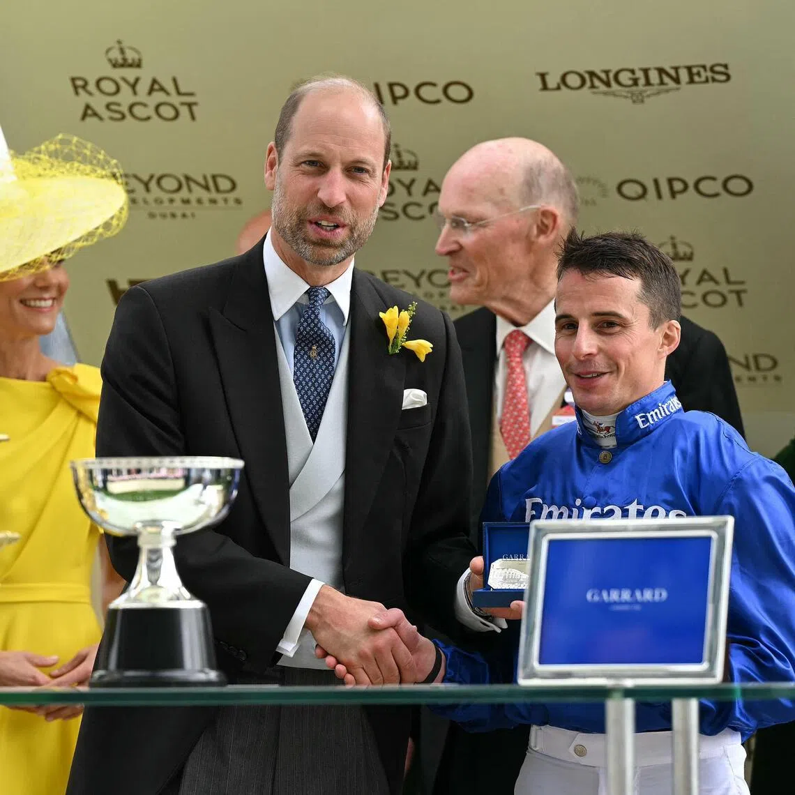 Britain's Prince William, Prince of Wales alongside his wife, Princess Catherine, Princess of Wales, presenting jockey William Buick, with trainer John Gosden standing behind, with his award for riding Ombudsman to win the Group 1 Prince Of Wales's Stakes (2,000m) on the second day of the Royal Ascot meeting in Ascot.