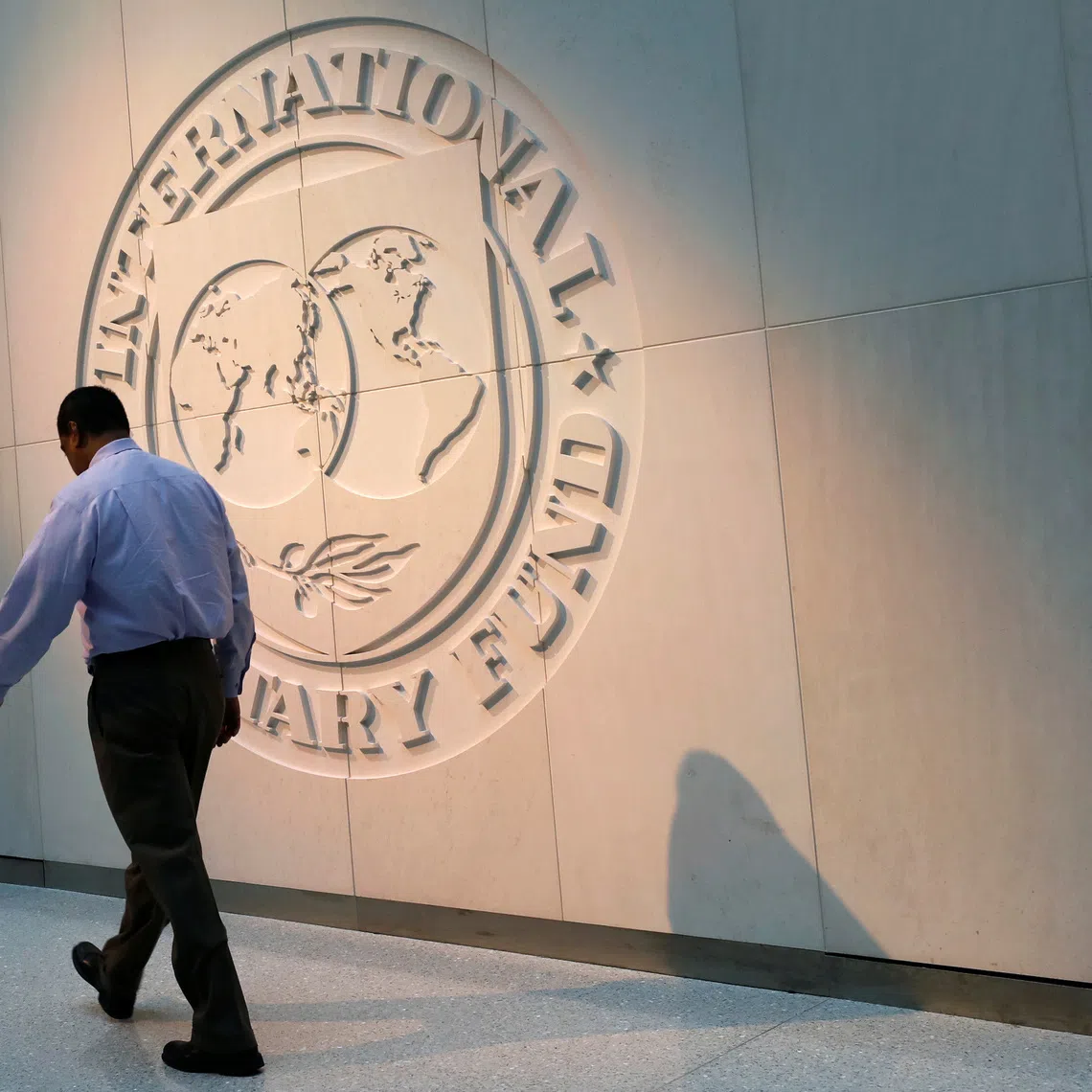 A man walks past the International Monetary Fund (IMF) logo at its headquarters in Washington, U.S., May 10, 2018. REUTERS/Yuri Gripas