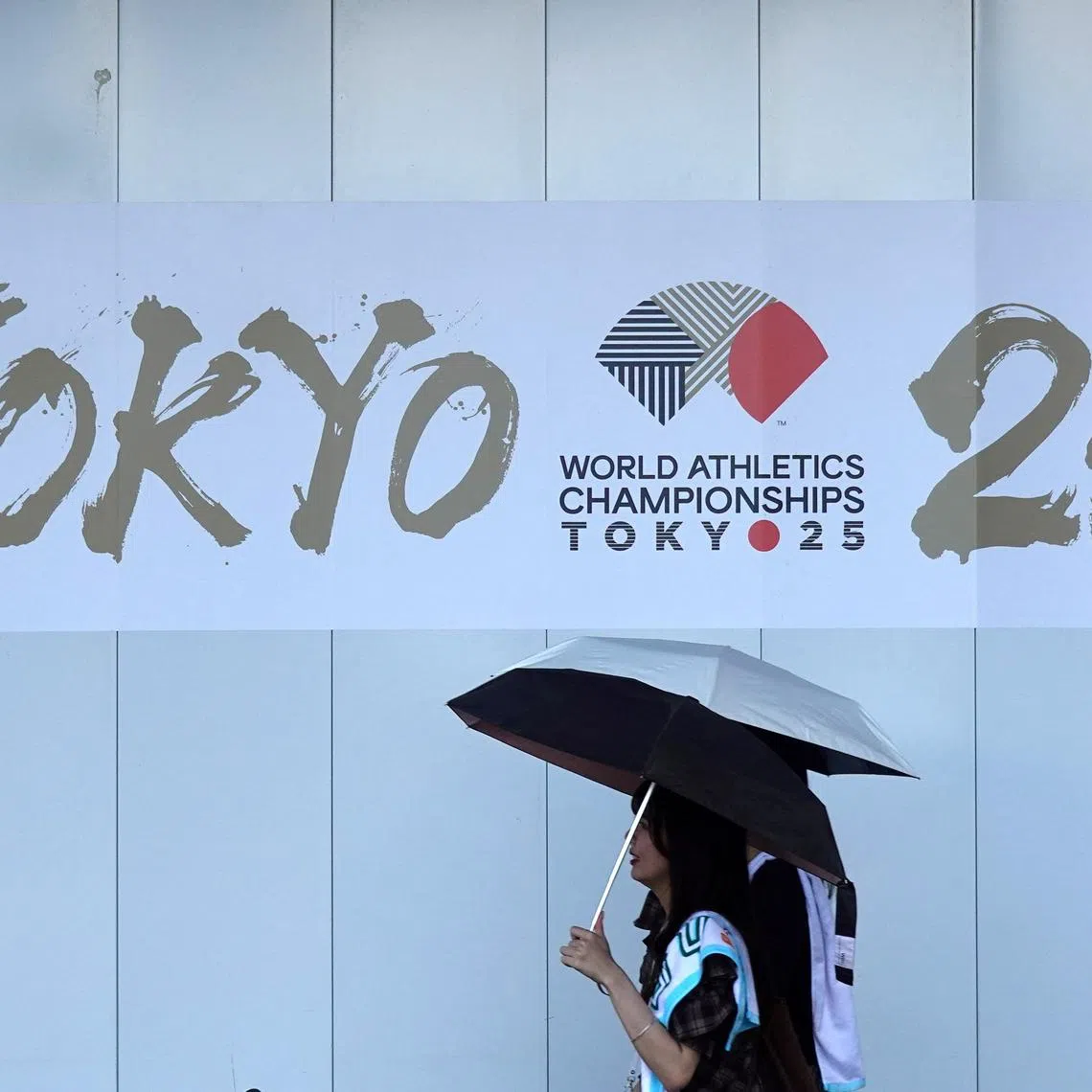 FILE PHOTO: People walk in front of an advertising banner for the upcoming World Athletics Championships Tokyo 25, near the National Stadium in Tokyo, Japan, September 6, 2025. REUTERS/Fabrizio Bensch/File Photo
