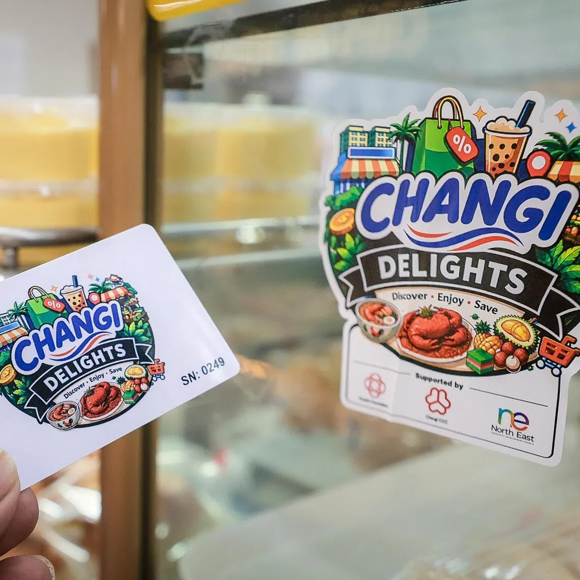 A Changi Delights Card and a sticker on a store at Loyang Point indicating acceptance of the card at the shopping centre on June 13, 2026.