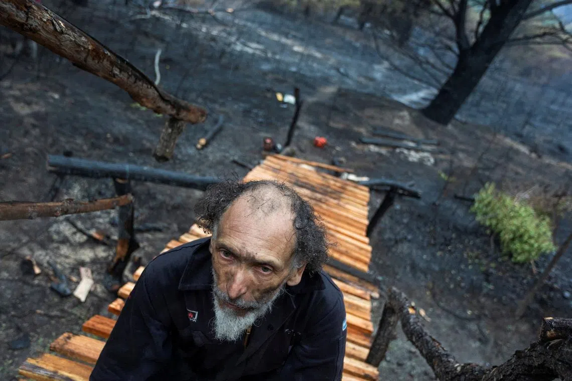 A man taking a break while working on building a wooden bridge in an area scorched by wildfires, in Epuyen, in the Patagonian province of Chubut, Argentina Jan 11, 2026. 